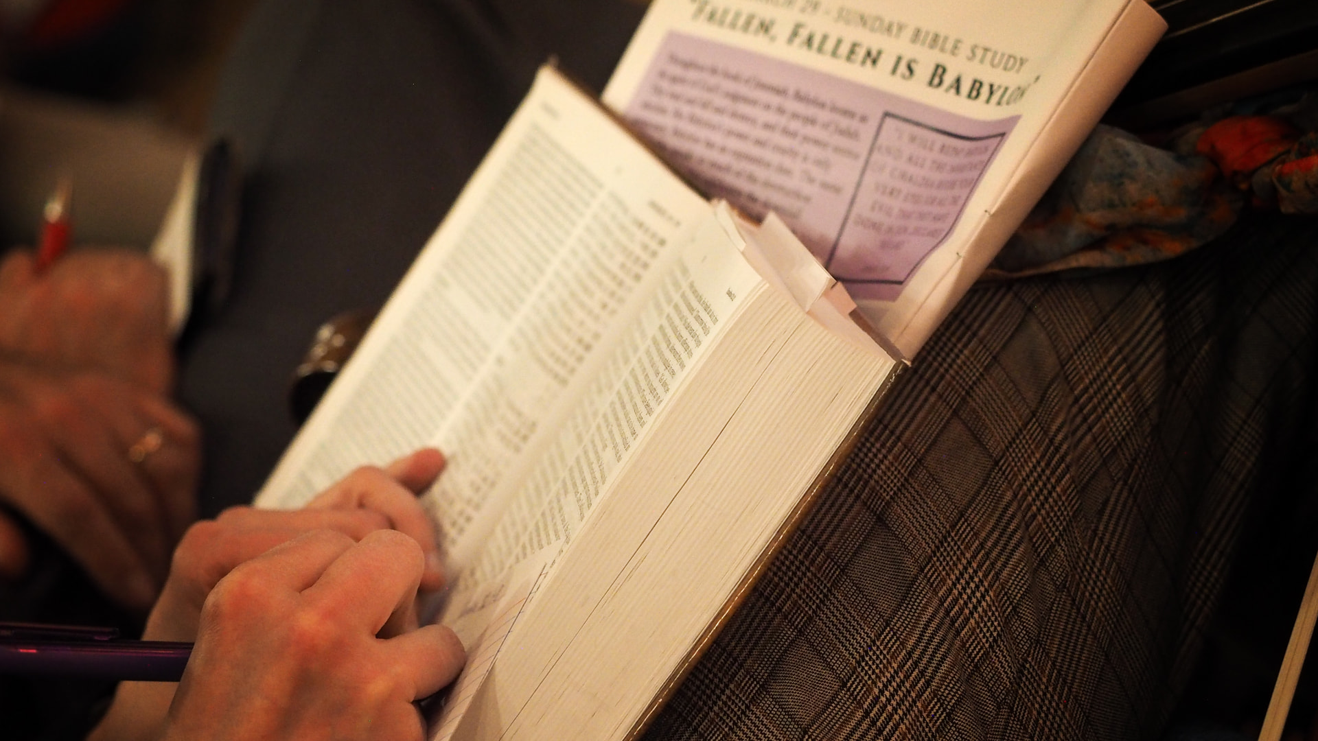 Hands taking notes in an open Bible during an adult Bible study