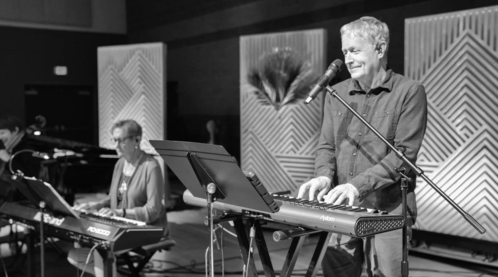 A Trinity worship team keyboardist singing while a second player accompanies on stage