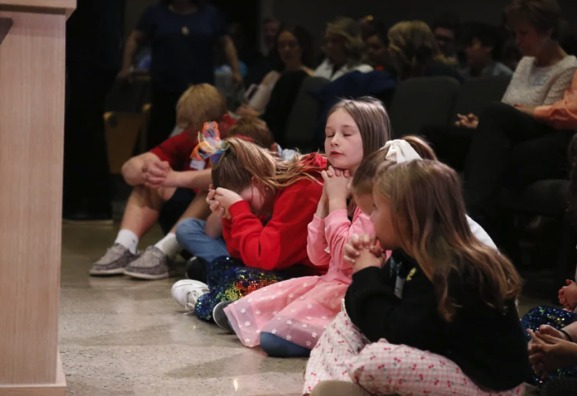 Young students praying together during chapel