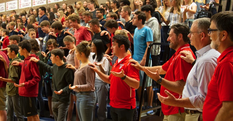 Students and staff worshipping together in the gym