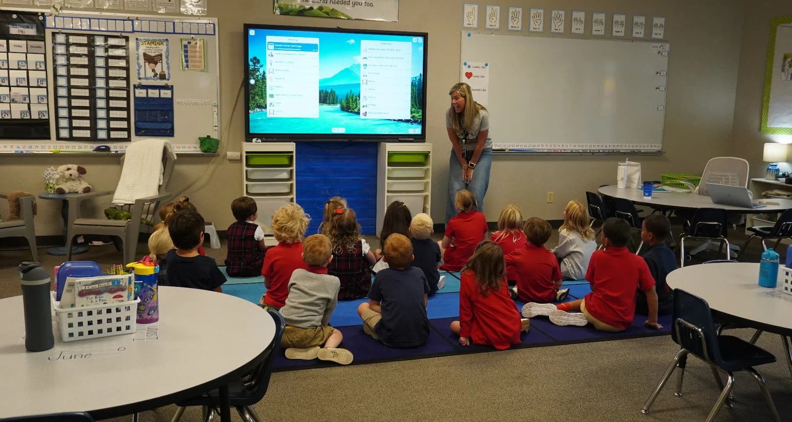 Trinity teacher and young students at a classroom smart board