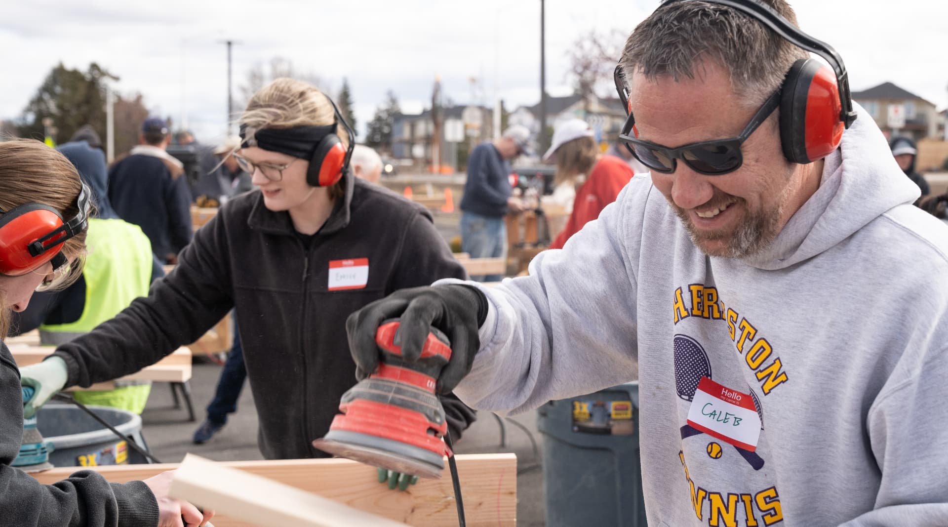Volunteers sanding and assembling wooden beds at an outdoor community build day