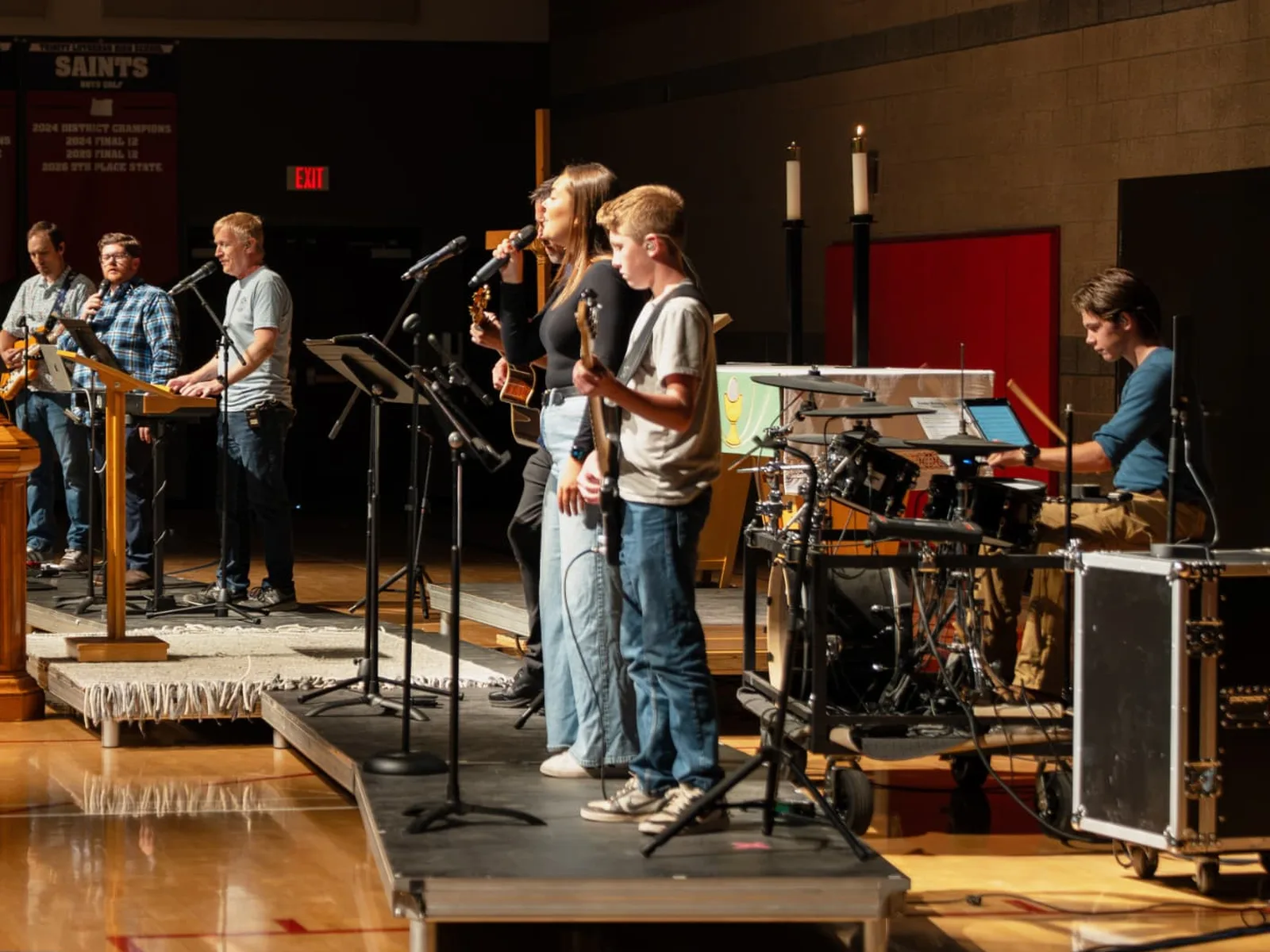 Students leading worship together in the school gym — a band with a singer, guitarist, bassist, and drummer