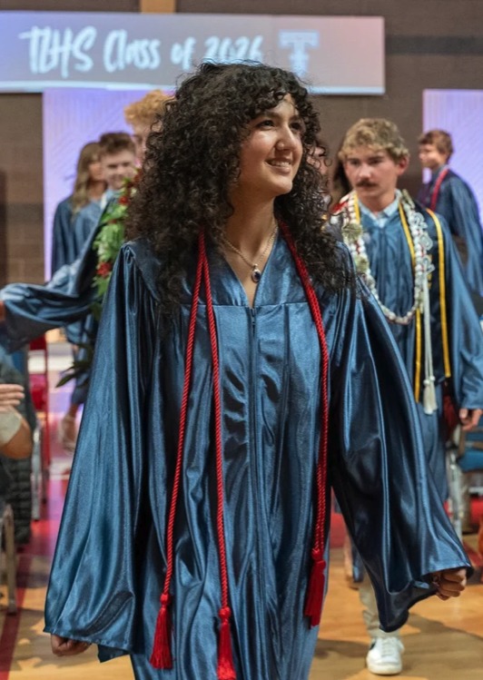 Trinity graduate in cap and gown smiling at commencement