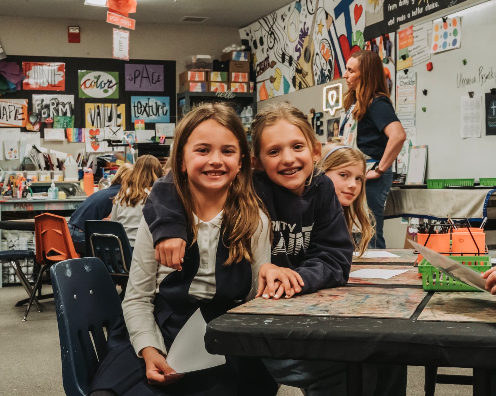 Lower School students smiling together in their art classroom